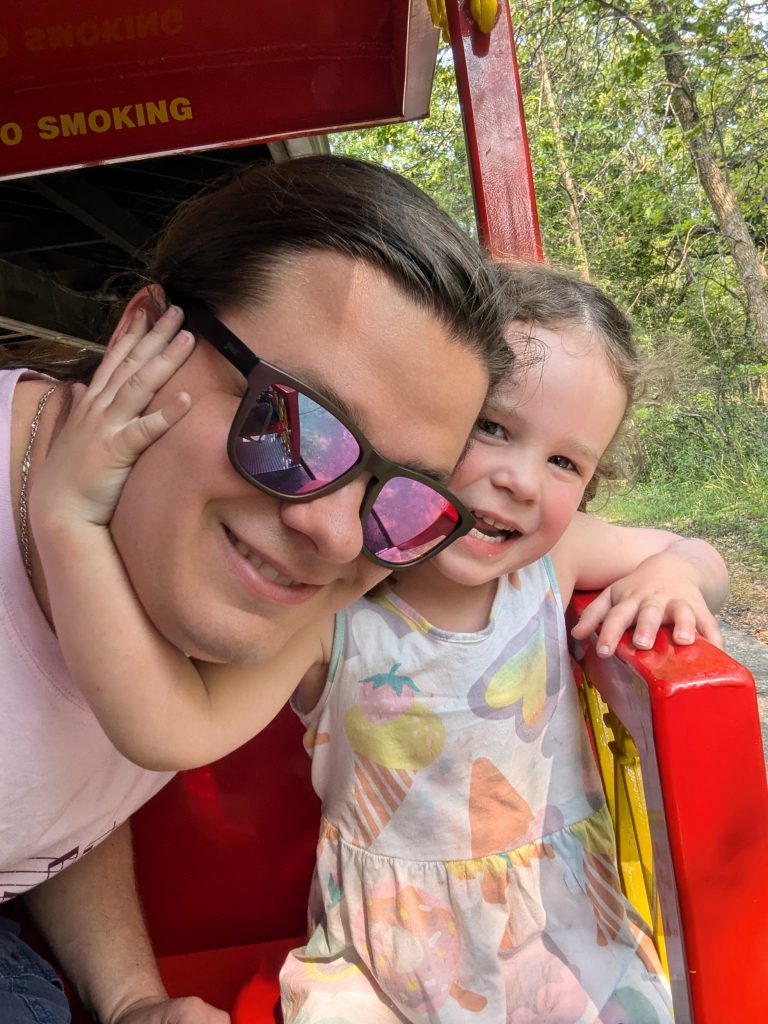 A photo of me and my daughter smiling and hugging on the steam train at Assiniboine Park